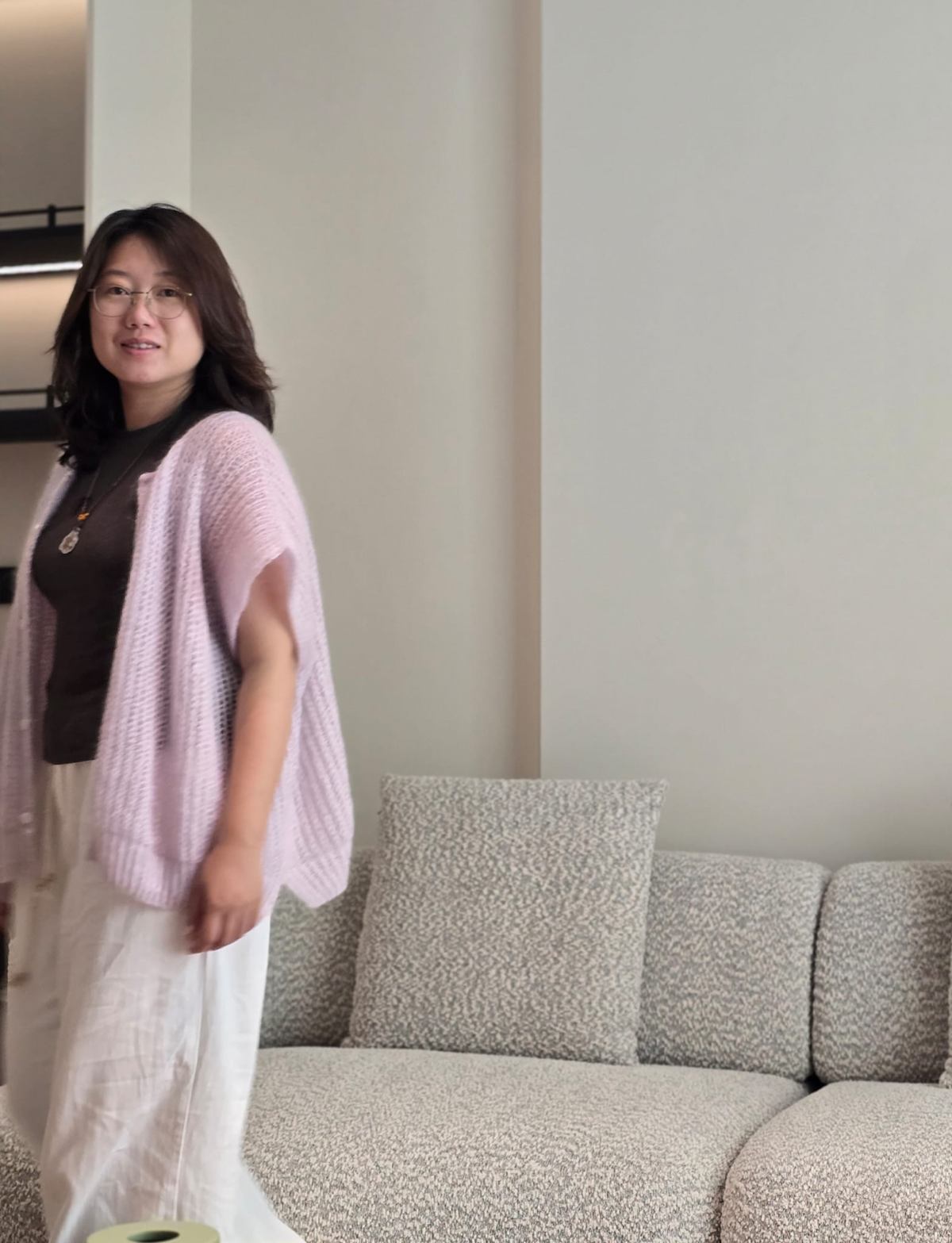 Yifan Wei, standing beside a textured boucle sofa.